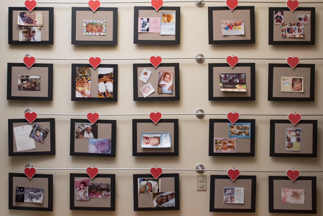 A wall of frames filled with photos of families, strung up with heart-shaped clips.