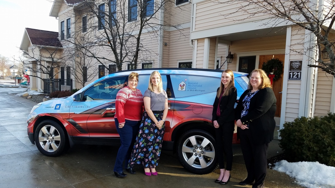 Four women standing in front of a car provided by GM