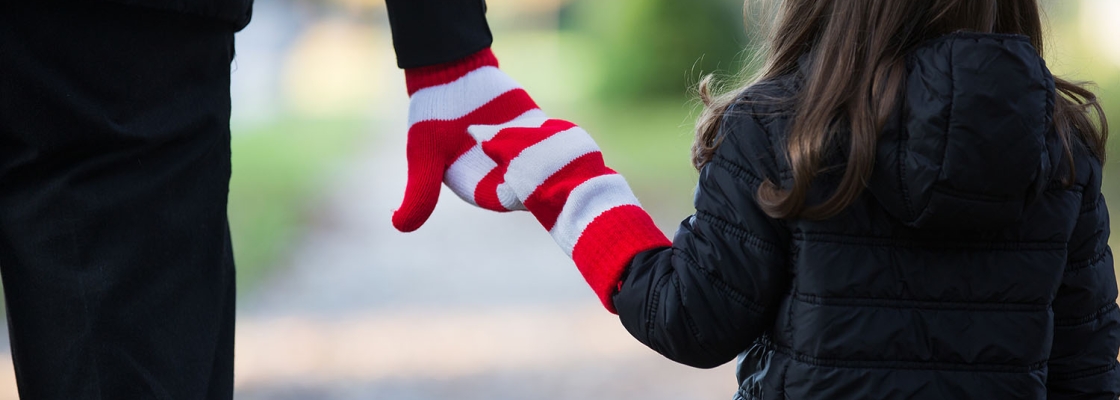 Adult and child holding hands wearing red and white striped gloves