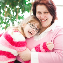 Mother and daughter hugging and smiling at the camera